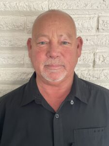 A man with a shaved head and beard wearing a black shirt.